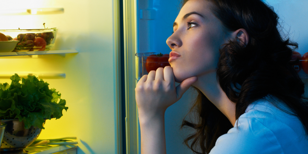 WOMAN GAZING INTO THE FRIDGE GETTING READY TO CLEAN IT