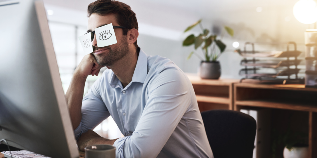 a man sitting at table with eyepatches over his eyes because of lack of sleep