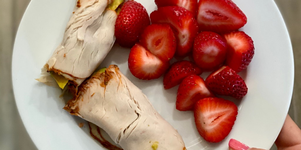 strawberries and rolled turkey on a plate showing snack that help with health goals